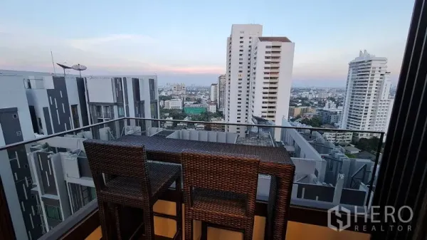公寓 出租在Watthana, Bangkok - 高楼阳台配吧椅，俯瞰傍晚的曼谷天际线。