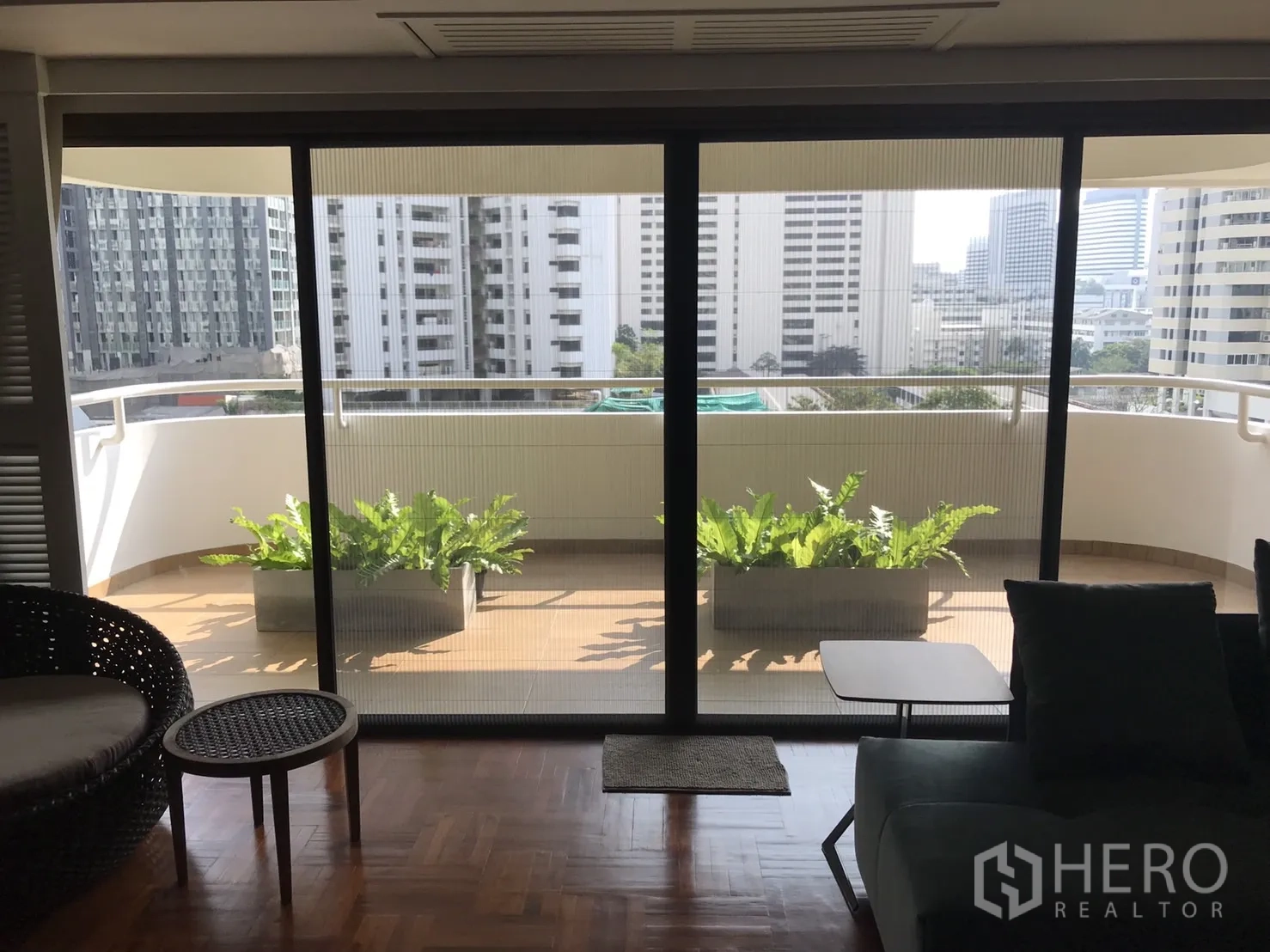 Condominium for rent in Bangkok - Large balcony with planter boxes and skyline views seen through sliding glass doors.