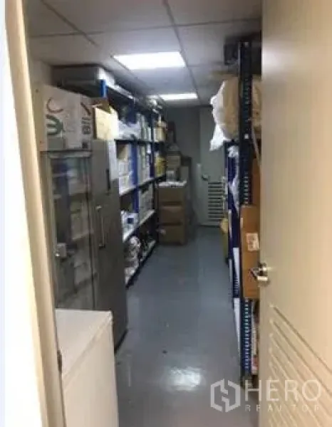 Office Space for rent in Khlong Toei, Bangkok - Narrow storage room lined with metal shelving and boxes under bright lighting.