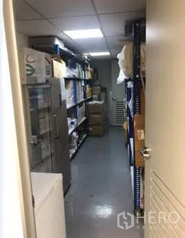 Office Space for rent in Khlong Toei, Bangkok - Narrow storage room lined with metal shelving and boxes under bright lighting.