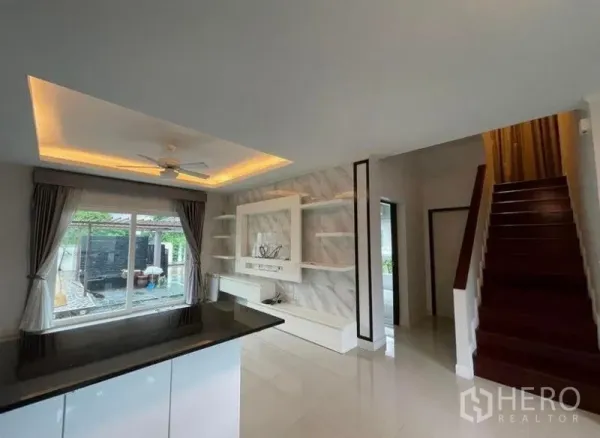 บ้าน ขายในBang Phli, Samut Prakan - มุมมองจากบาร์ครัวไปยังผนังทีวี บันได และหน้าต่างที่มองเห็นสระ