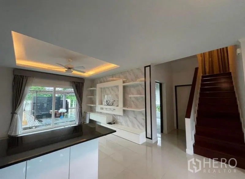 บ้าน ขายในBang Phli, Samut Prakan - มุมมองจากบาร์ครัวไปยังผนังทีวี บันได และหน้าต่างที่มองเห็นสระ