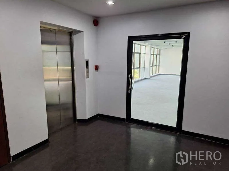 办公空间 出租 - 电梯厅配不锈钢电梯与玻璃门，通向采光充足的办公层。
