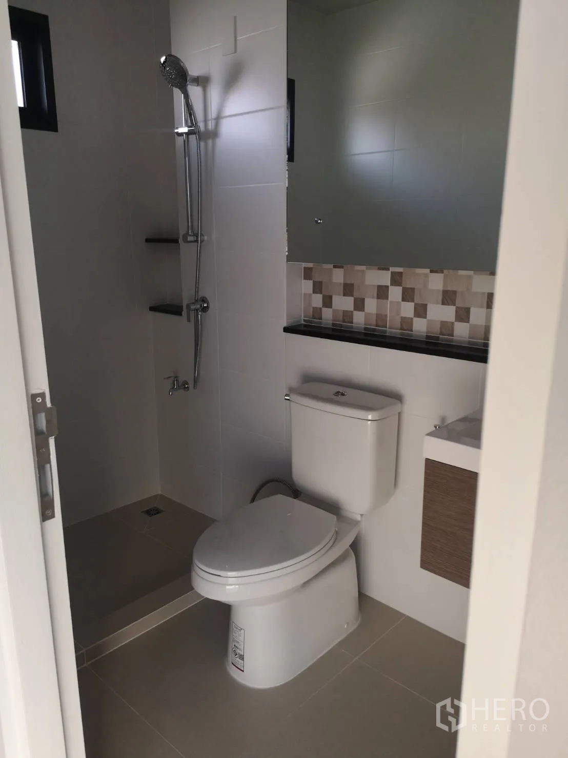 Detached House for sale in Lam Luk Ka, Pathum Thani - Guest bathroom featuring a walk-in shower, toilet and compact vanity.