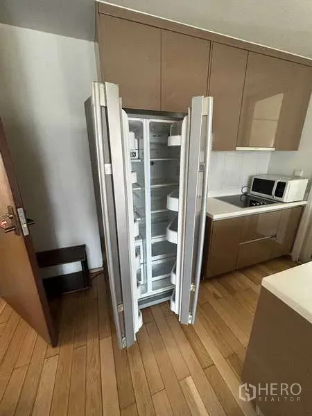 Condominium for rent in Khlong Toei, Bangkok - Modern kitchen with open side-by-side refrigerator and built-in cabinets.