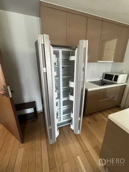 Condominium for rent in Khlong Toei, Bangkok - Modern kitchen with open side-by-side refrigerator and built-in cabinets.