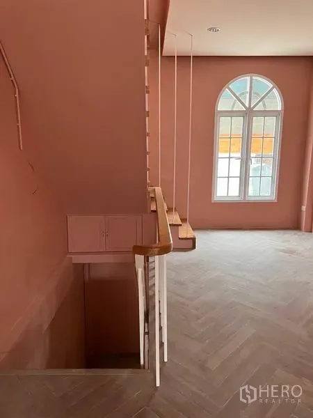 Shophouse for rent or sale in Watthana, Bangkok - Pastel-pink shophouse interior with herringbone floor, wooden stairs and arched window.