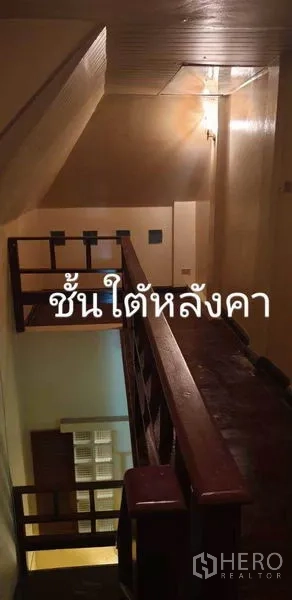 Townhouse for rent in Phra Khanong, Bangkok - Stairwell and top-floor landing with wooden handrails under the roof.