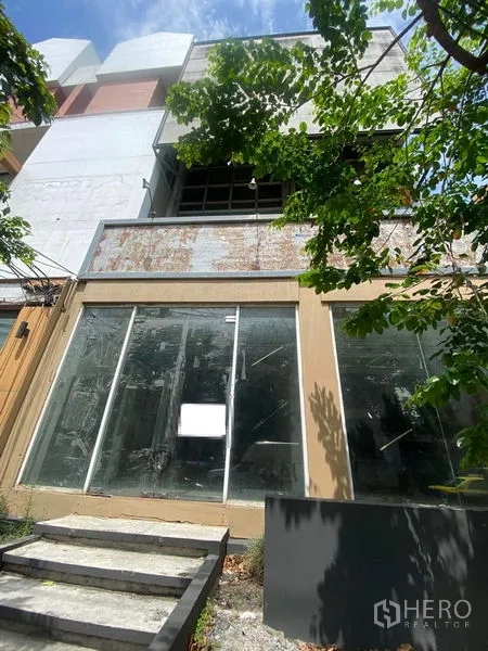 Shophouse for sale in Watthana, Bangkok - Street-facing multi-storey shophouse with wide floor-to-ceiling glass storefront and shaded entry in Ekkamai, Bangkok.