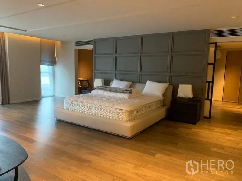 公寓 出租在Watthana, Bangkok - 宽大的主卧，饰板床头墙、木地板与柔和灯光。