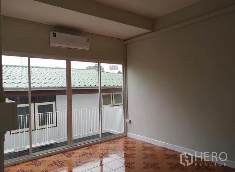 Townhouse for rent or sale in Din Daeng, Bangkok - Upper-floor bedroom with full-width glass doors to a balcony and patterned tile floor.