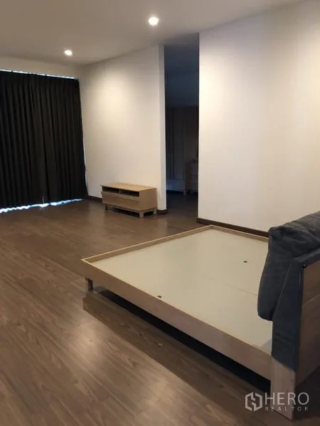 独立式住宅 出租在Prawet, Bangkok - 宽敞主卧，木地板、床架、筒灯与遮光窗帘。