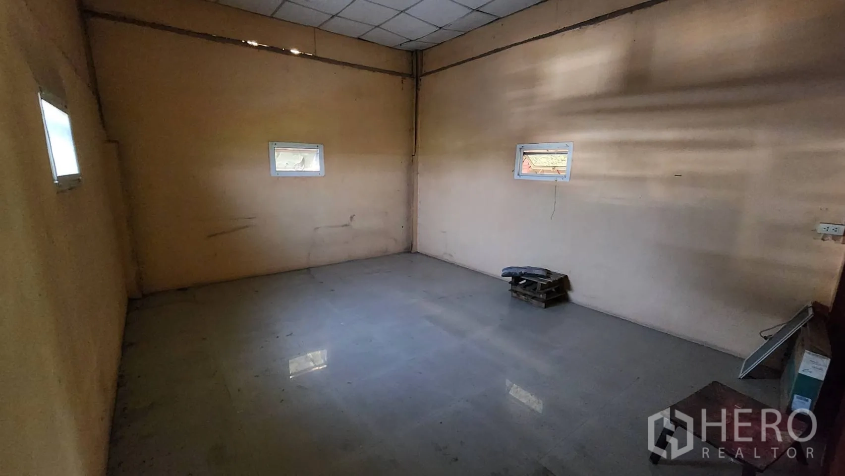 Warehouse for rent in Nonthaburi - Small upstairs room with tiled floor and two windows.