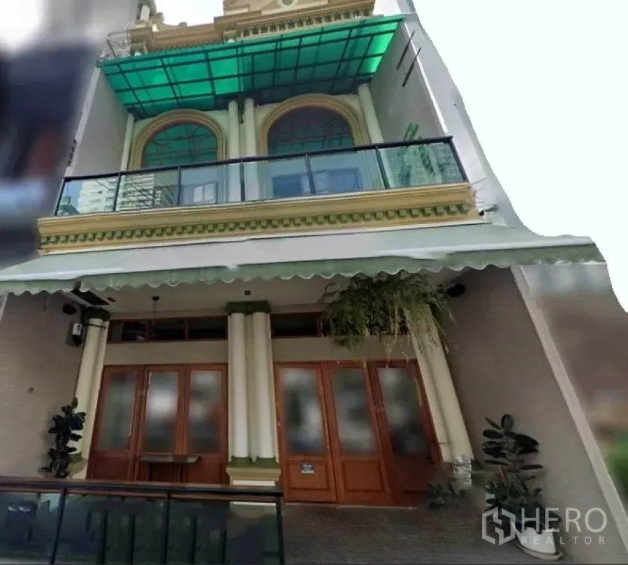Shophouse for rent in Watthana, Bangkok - Street-facing facade of the shophouse showing double columns, arched windows, a glass balcony, and a wide awning.
