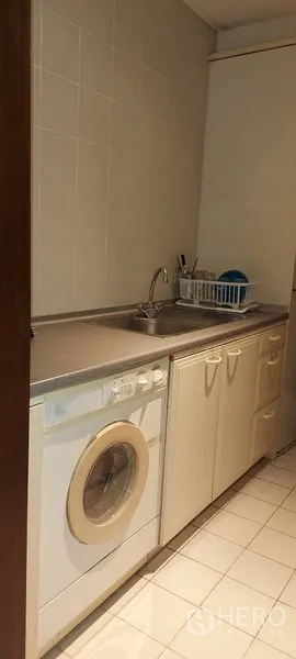 Condominium for rent in Sathon, Bangkok - Laundry area with washing machine, sink and storage cabinets.