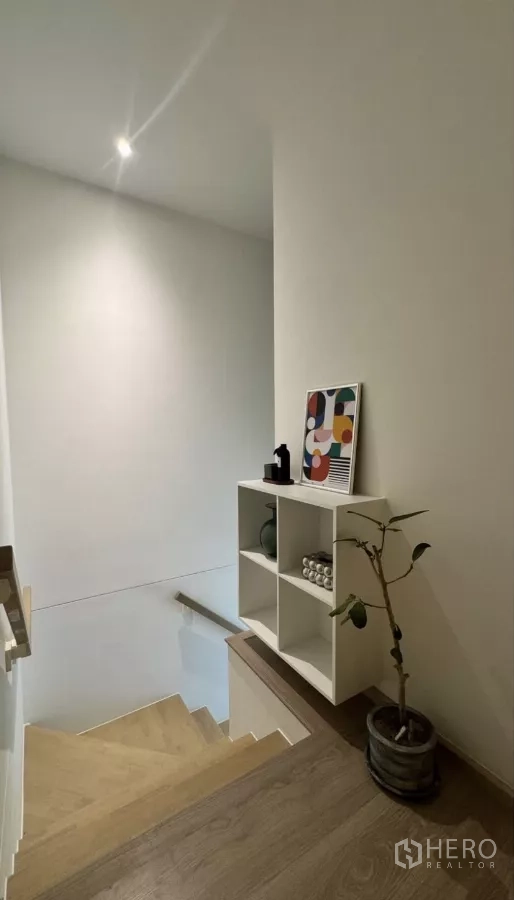 Townhouse for rent in Bang Phli, Samut Prakan - Timber staircase with display shelf and potted plant at the landing.