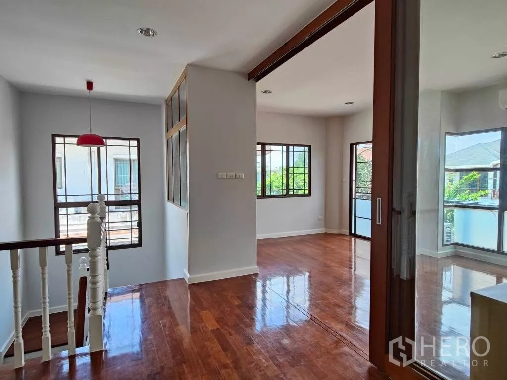 独立式住宅 出租或出售在Mueang Nonthaburi, Nonthaburi - 楼梯平台挂红色吊灯，通往多间卧室。