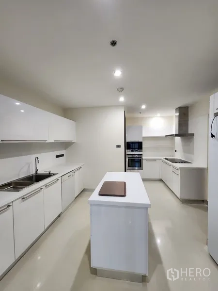 Condominium for rent in Khlong Toei, Bangkok - Fully fitted white kitchen with island, ample cabinets and double sink.