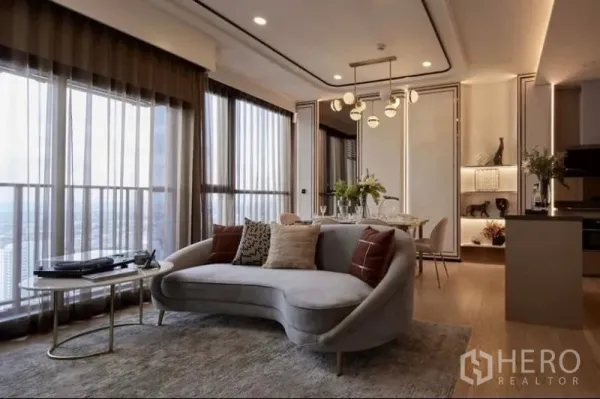 公寓 出售在Watthana, Bangkok - 转角客厅空间，弧形沙发、圆形边几与整面落地玻璃。