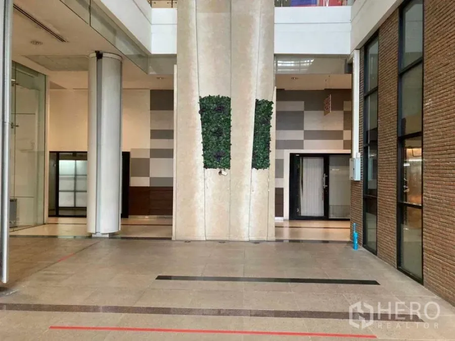 Retail Space for rent in Khlong Toei, Bangkok - Modern retail atrium with high ceiling, glass storefronts, brick accent wall, tiled floor, and vertical green wall feature.