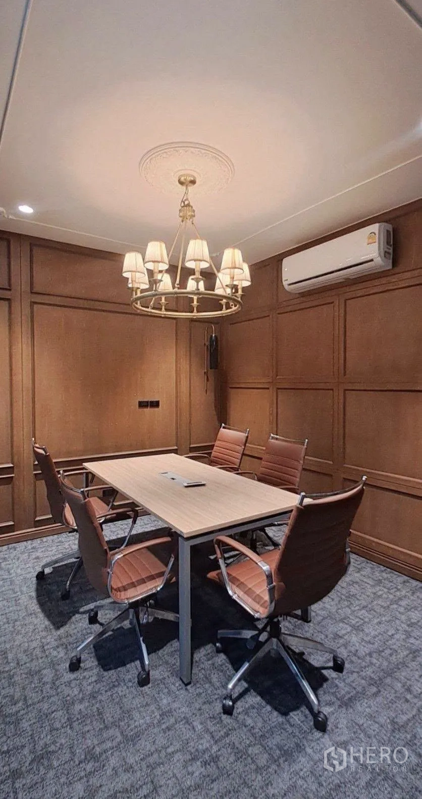 Home Office for rent in Lat Phrao, Bangkok - Meeting room with chandelier, wood wall panels and table with chairs.