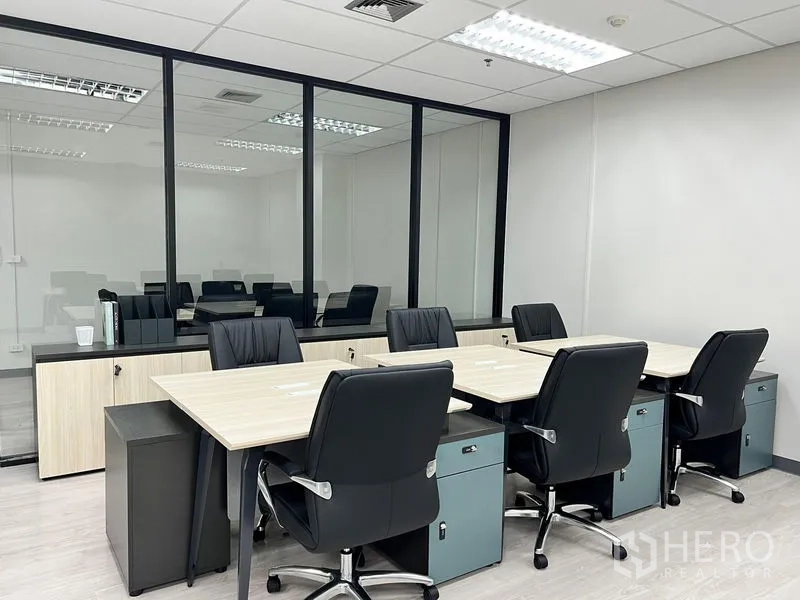 Office Space for rent in Sathon, Bangkok - Team area by a glass partition featuring four desks and a low storage credenza.