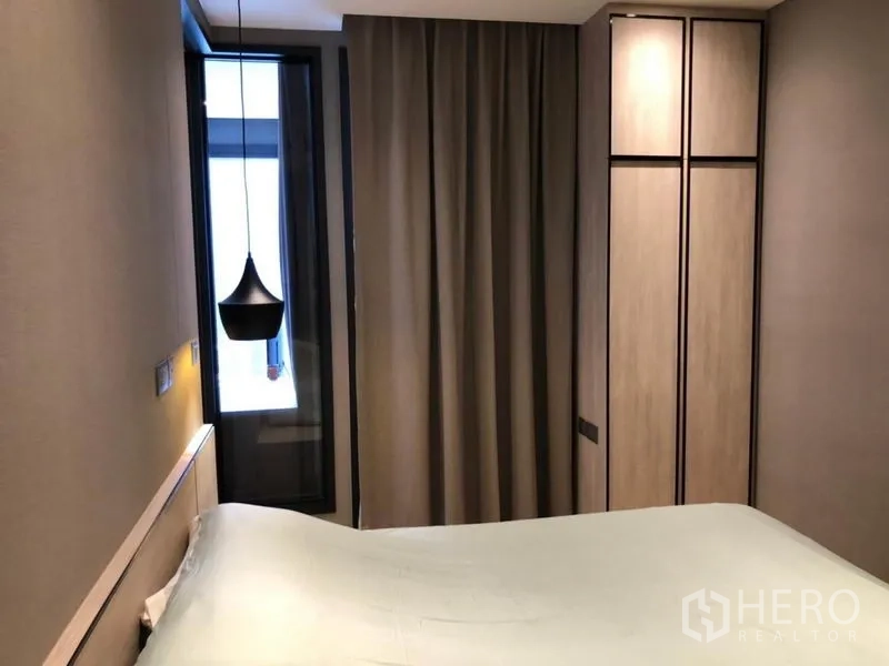 Condominium for rent in Din Daeng, Bangkok - Bedroom with tall wardrobe, blackout curtains, and narrow window bringing natural light.