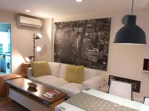 公寓 出租在Watthana, Bangkok - 温馨客厅，城市风景壁画、吊灯与墙式空调。