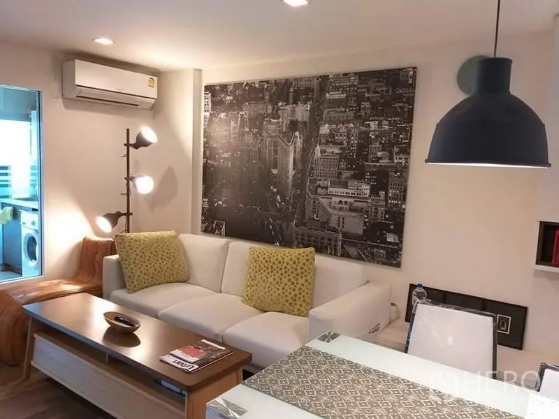 公寓 出租在Watthana, Bangkok - 温馨客厅，城市风景壁画、吊灯与墙式空调。