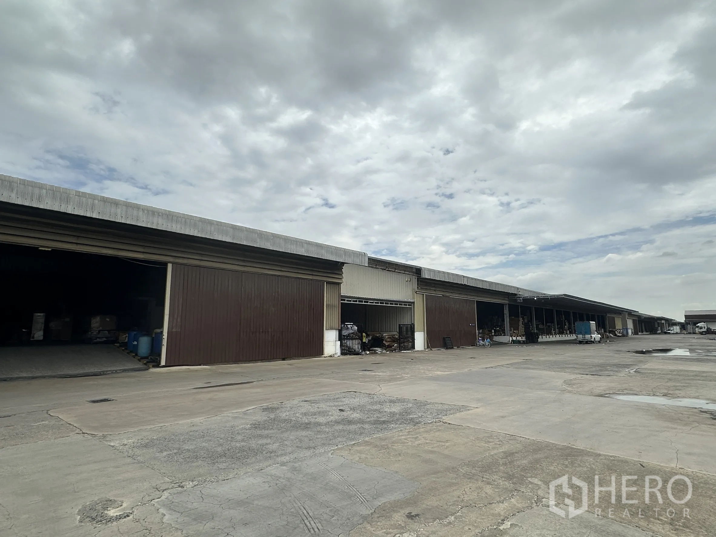 工厂 for rent in Lat Krabang, Bangkok - 一排相连仓库单元配卷帘门，前方为宽阔硬化车道。