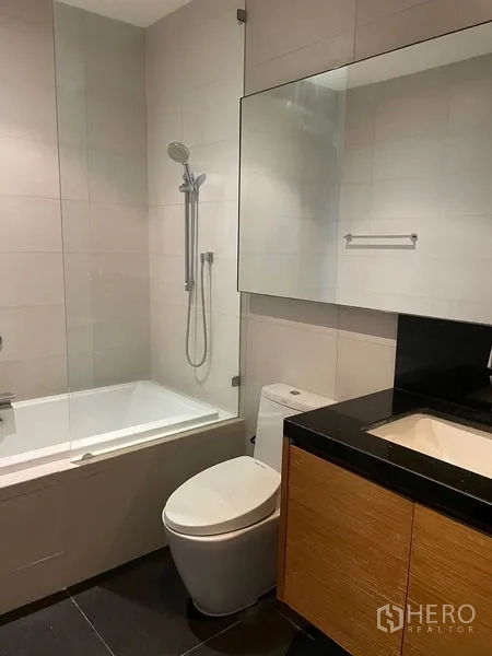 公寓 出租在Watthana, Bangkok - 当代风格卫浴，带浴缸、玻璃隔断、台盆与马桶。