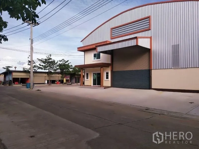 Warehouse for rent or sale in Nakhon Pathom - Street view of the warehouse with wide apron for truck access along a paved road.