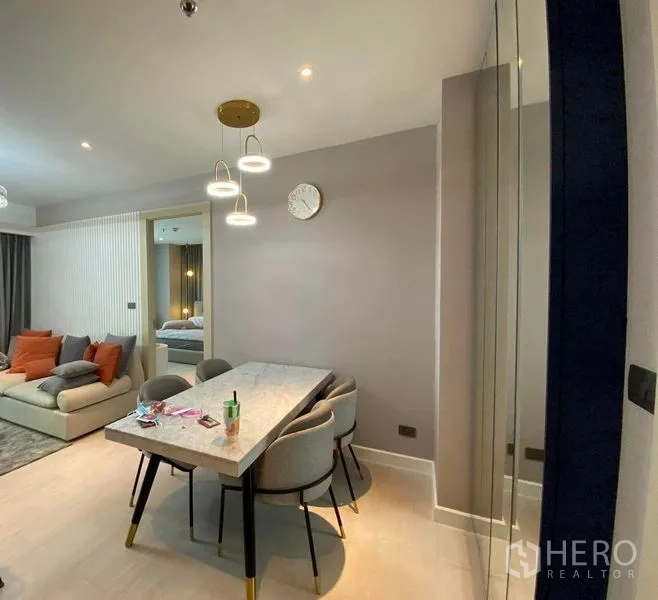 Condominium for sale in Huai Khwang, Bangkok - Dining nook with marble table and four upholstered chairs beneath contemporary pendant lights.