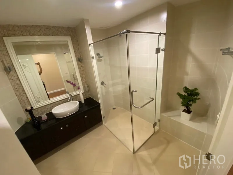 Apartment for rent in Watthana, Bangkok - Modern bathroom featuring a glass-enclosed shower, vanity and neutral tiles.