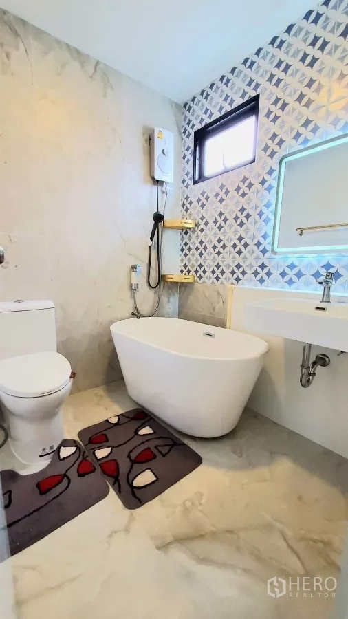 Detached House for rent in Lat Krabang, Bangkok - Modern bathroom with freestanding bathtub, shower, toilet, patterned wall tiles and a window.