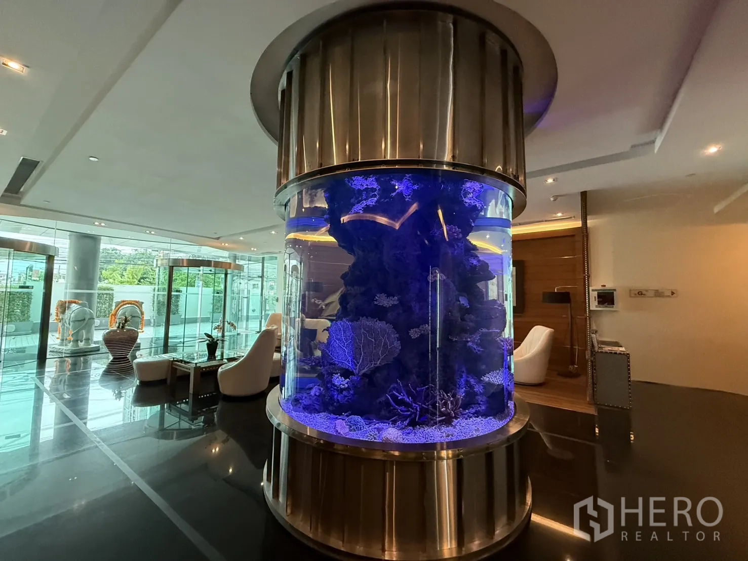 公寓 出租在Phaya Thai, Bangkok - 时尚公寓大堂，圆筒形水族箱与休闲座椅。