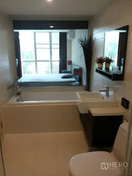 公寓 出租在Phaya Thai, Bangkok - 现代浴室，配浴缸、洗手台，并通过窗户可看到带大窗的卧室。