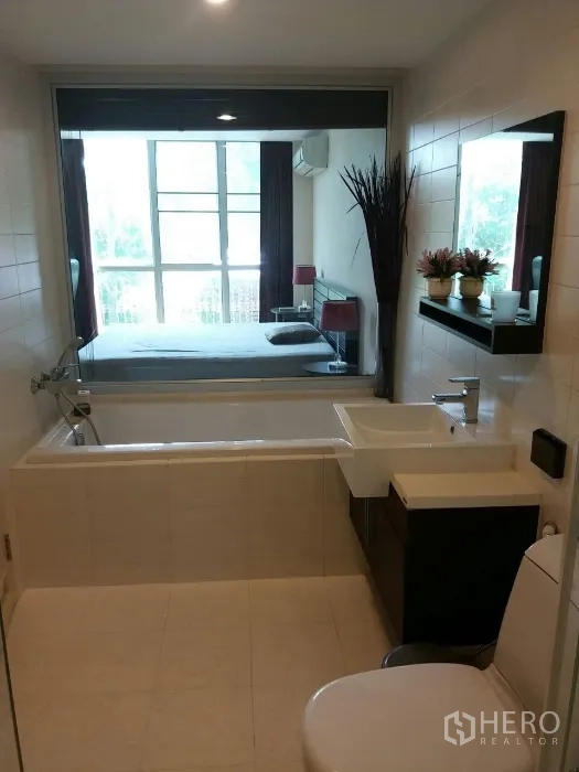 公寓 出租在Phaya Thai, Bangkok - 现代浴室，配浴缸、洗手台，并通过窗户可看到带大窗的卧室。