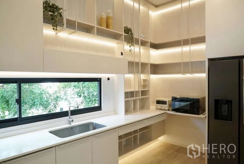 Detached House for rent in Saphan Sung, Bangkok - Light wood kitchen with long countertop, picture window and open shelving.