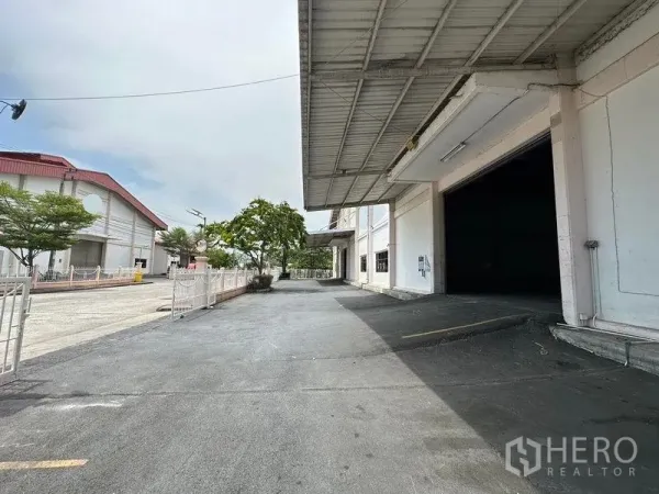 Warehouse for rent in Bang Sao Thong, Samut Prakan - Covered loading bay with ramp and paved yard alongside the warehouse building.