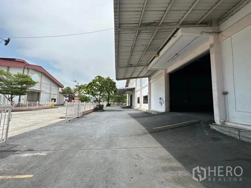 Warehouse for rent in Bang Sao Thong, Samut Prakan - Covered loading bay with ramp and paved yard alongside the warehouse building.