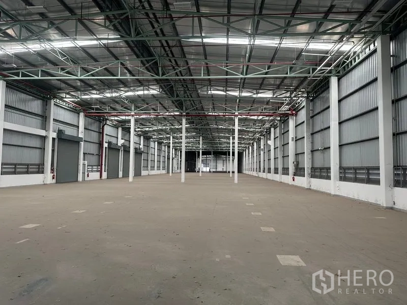 Factory for rent in Bang Sao Thong, Samut Prakan - Warehouse interior showing several loading bay doors along the side wall and a tall roof.