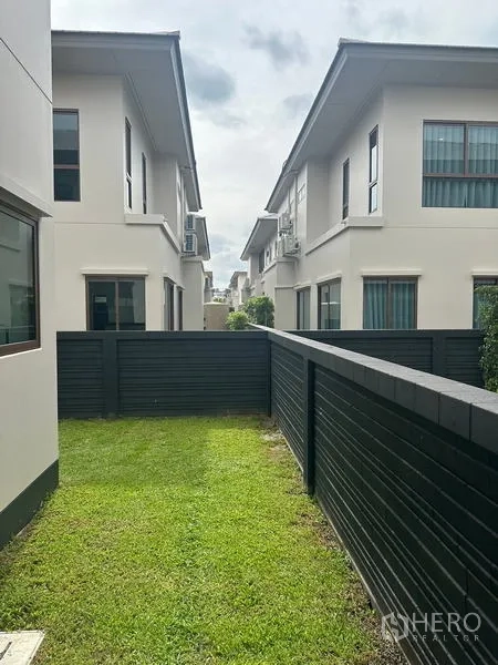 独立式住宅 出租在Bang Kapi, Bangkok - 后院草坪位于黑色私密围栏与邻屋之间。