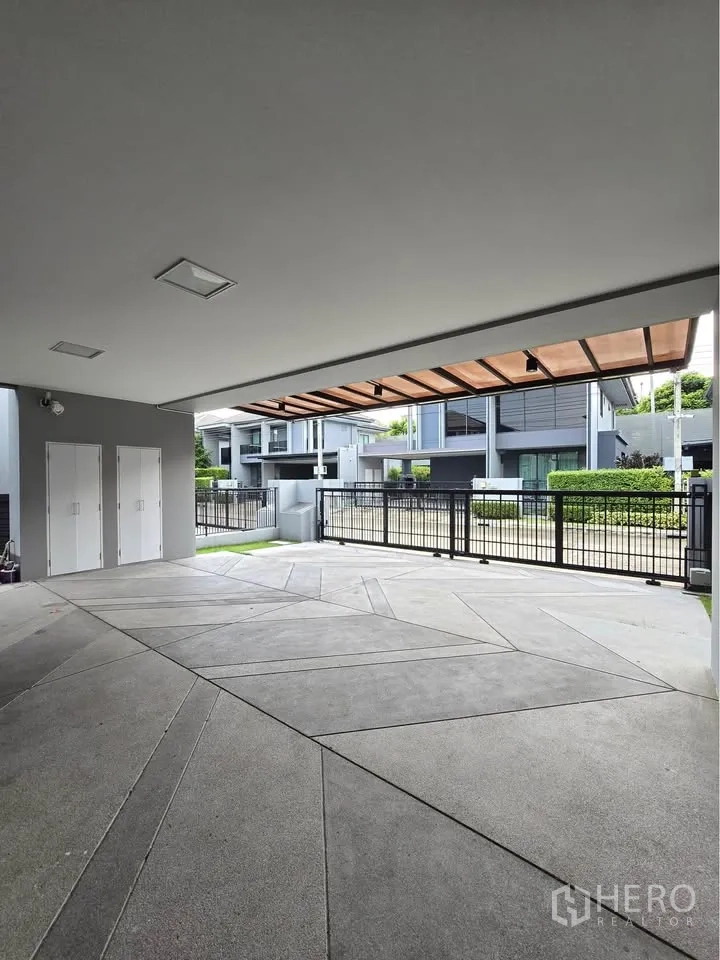 Detached House for rent in Bang Kapi, Bangkok - Covered carport with sliding gate and views of modern neighboring houses.