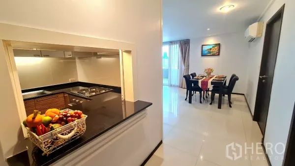 房间 出租在Watthana, Bangkok - 走廊与厨房的传菜窗，黑色花岗岩台面与水果篮