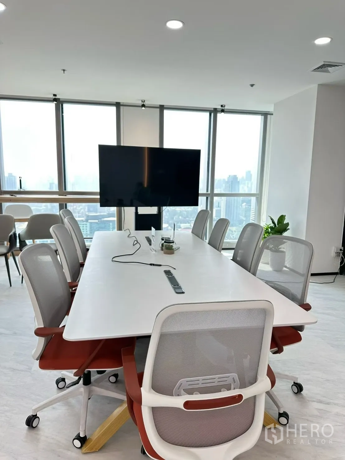Office Space for rent in Huai Khwang, Bangkok - Boardroom with white table, swivel chairs and large TV display beside city-facing windows.