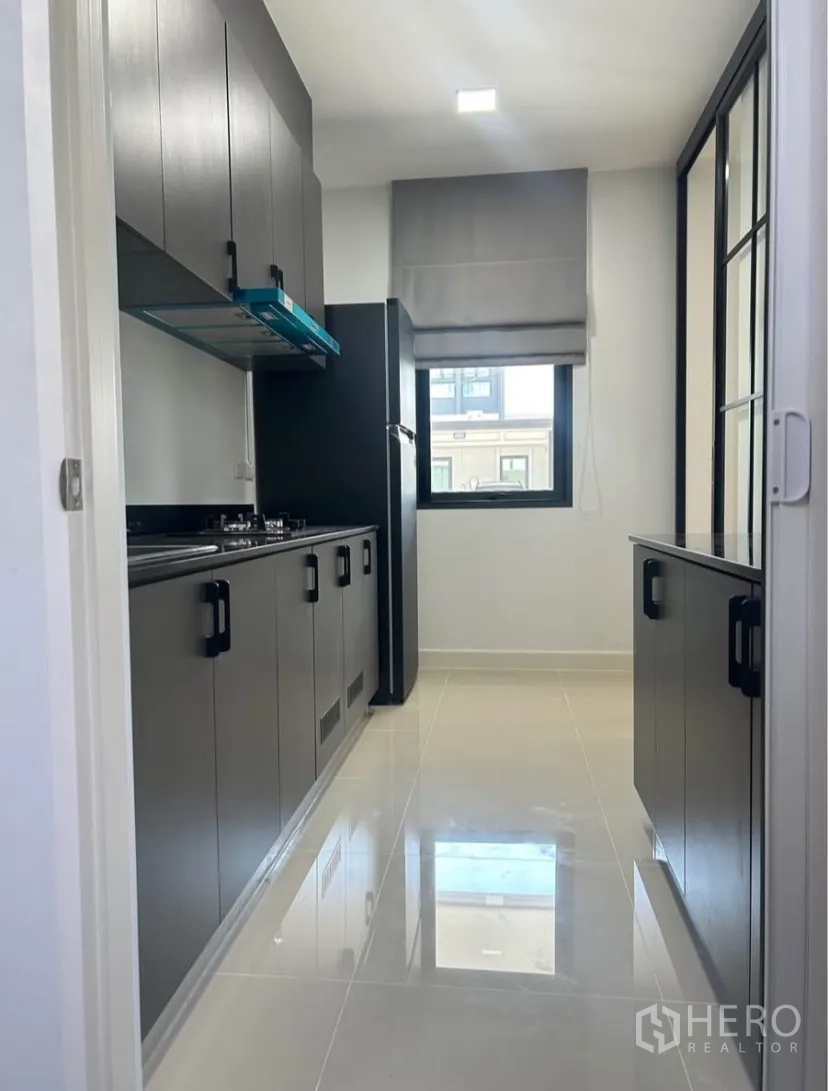 Semi-detached House for rent in Bang Phli, Samut Prakan - Sleek galley kitchen with dark cabinetry, gas hob, range hood and refrigerator.