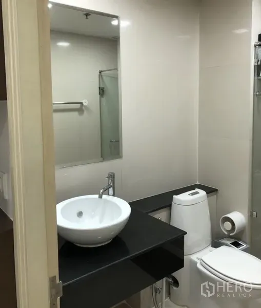 公寓 出租在Khlong Toei, Bangkok - 浴室设台上盆、宽镜与相邻的玻璃淋浴房。