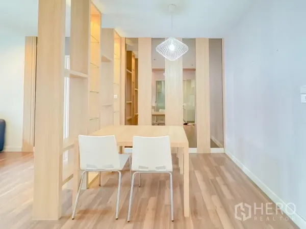 Condominium for sale - Dining area with wooden partition shelving, two white chairs and a pendant light.