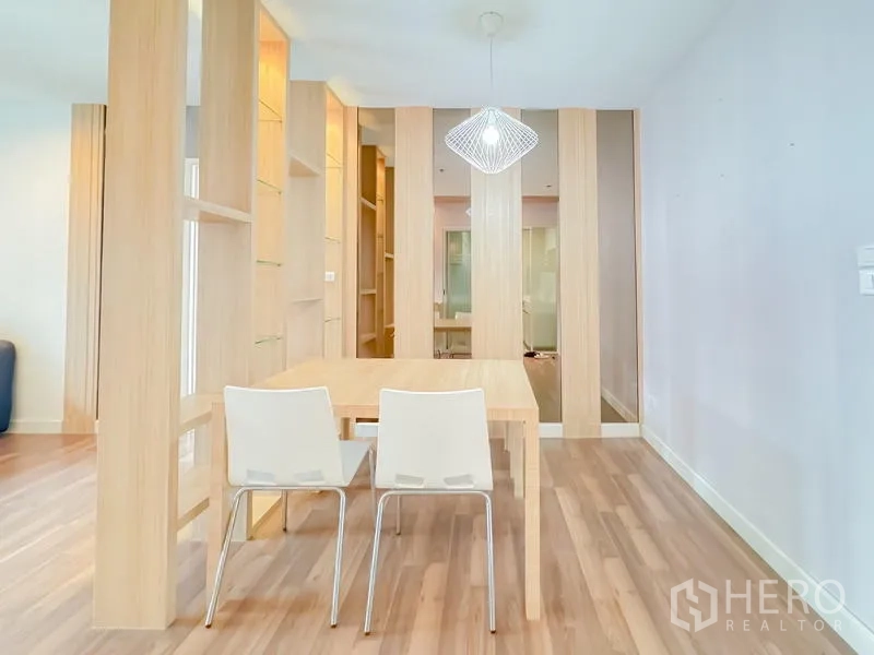 Condominium for sale - Dining area with wooden partition shelving, two white chairs and a pendant light.
